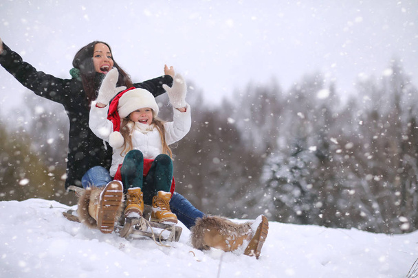 A winter fairy tale, a young mother and her daughter ride a sled - Foto, Bild