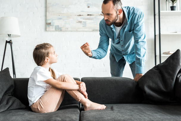 enojado padre amenazando con el puño y de pie cerca molesto hija en casa
  - Foto, Imagen