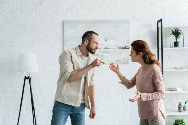 bearded man standing and pointing with finger at attractive woman  - Photo, Image