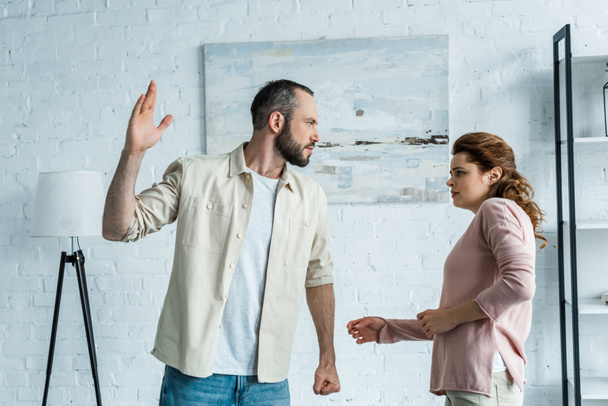 scared woman looking at aggressive husband gesturing at home  - Фото, изображение