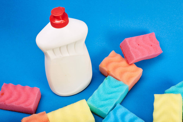 Bottle with cleanser and sponges on blue background - Photo, image
