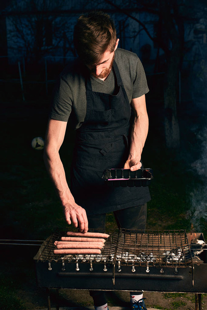 Man cooking sausages on grill  - Фото, изображение