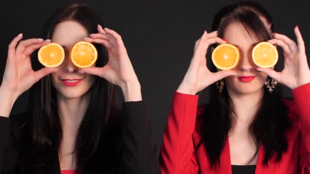 Naiset pitelevät puolitettuja appelsiineja silmiensä edessä
. - Materiaali, video