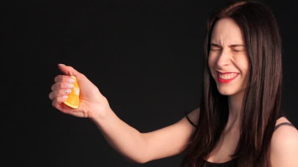 Crazy young brunette squeezing orange in hand - Footage, Video