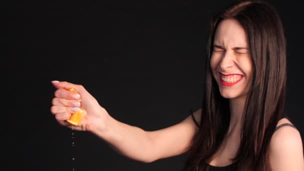 Сумасшедшая юная брюнетка сжимает апельсин в руке
 - Кадры, видео