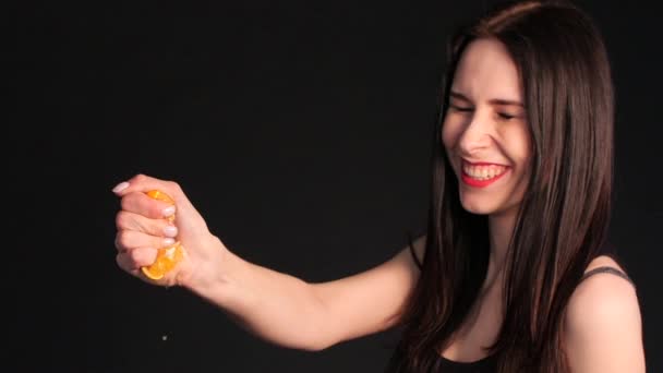 Szalona młoda brunetka wyciskająca pomarańczowy w ręku - Materiał filmowy, wideo