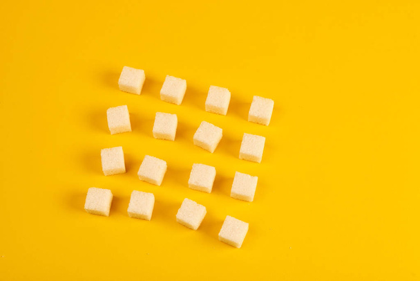 Arranged sugar cubes on yellow background  - Fotoğraf, Görsel