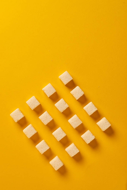 Arranged sugar cubes on yellow background  - Fotó, kép