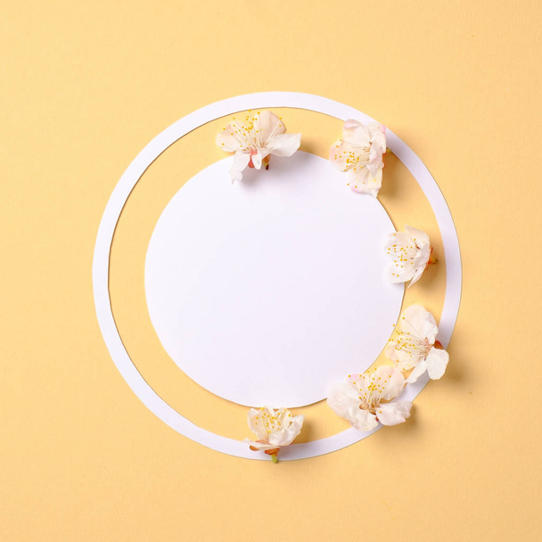 Creative flat lay composition: circle blank paper and blooming sakura petals on yellow background. Top view, floral frame, abstract design. Invitation, greeting card or an element for your design - Fotografie, Obrázek