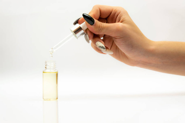 Cosmetische Pipetteer met druppels cosmetische olie close-up op een witte achtergrond  - Foto, afbeelding