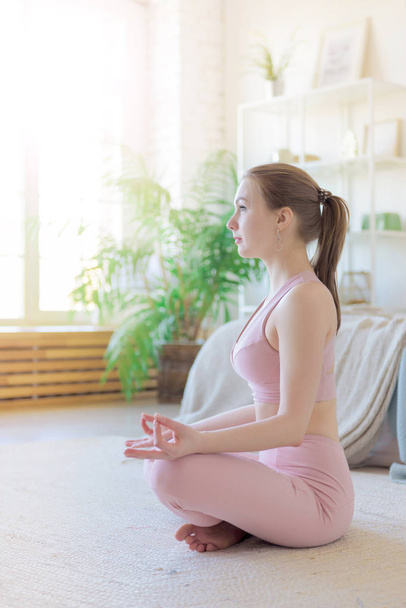 Desporto jovem, mulher pratica ioga dentro de casa. Asana ioga, conceito de saúde, ioga no meu coração
 - Foto, Imagem