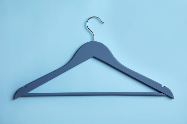 Empty wooden clothes hanger on color background, top view - Foto, afbeelding