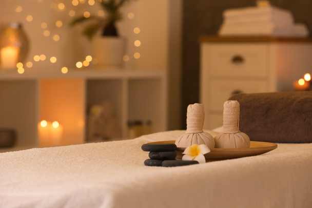 Herbal compresses and stones on massage table in spa salon. Space for text - Photo, Image
