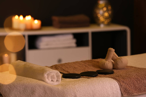 Herbal compresses and stones on massage table in spa salon - Photo, Image