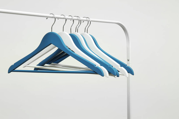 Άδειοι κρεμάστρες ρούχων σε μεταλλική σχάρα από ανοιχτόχρωμο φόντο - Φωτογραφία, εικόνα