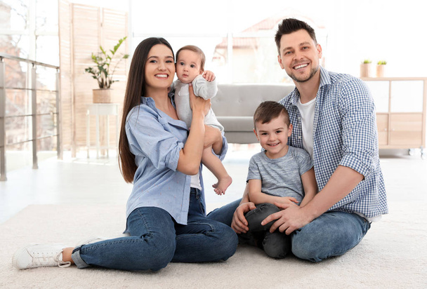 Happy couple with children sitting on floor at home. Family weekend - Photo, image