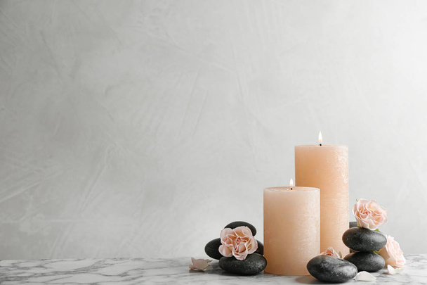 Composition of burning candles, spa stones and flowers on table. Space for text - Foto, Imagem