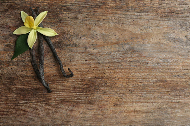 Composition plate avec bâtonnets de vanille et fleur sur fond en bois. Espace pour le texte
 - Photo, image