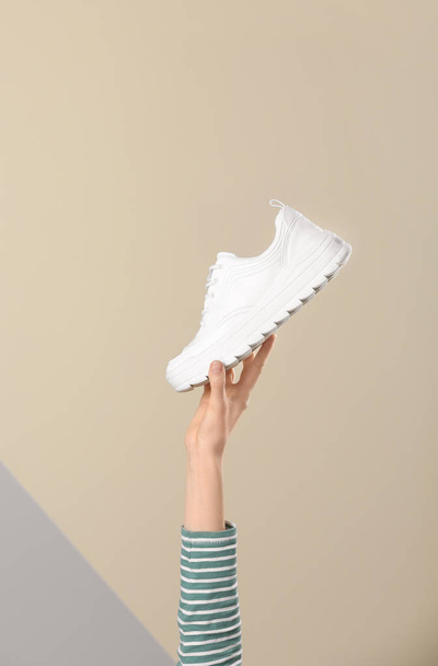 Woman holding sportive shoe on color background, closeup. Space for text - Foto, Bild