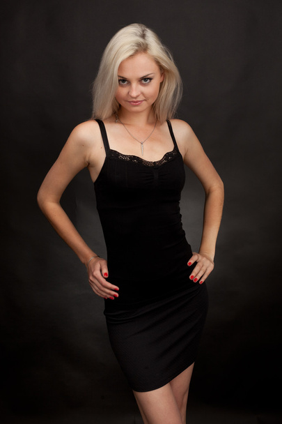 Beautiful girl in a short black dress on a black background - Foto, imagen