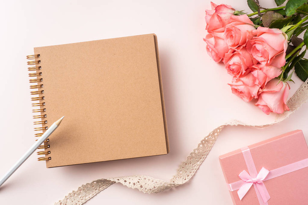 Bouquet of pink roses, gift box, notebook, pencil and vintage ribbon on pink background - Valokuva, kuva