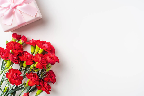 Bouquet of red carnations and gift box on background with copy space - Foto, imagen
