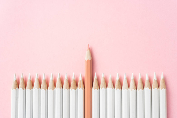 Business and design concept - lot of white pencils and one color pencil on pink paper background. Symbol of leadership, teamwork, success and unique. - Photo, Image