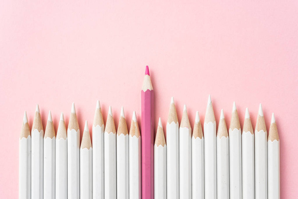 Business and design concept - lot of white pencils and one color pencil on pink paper background. Symbol of leadership, teamwork, success and unique. - Photo, Image