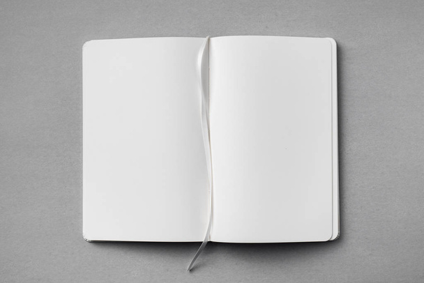 Top view of opened white notebook with ribbon bookmark on grey background for mockup. - Foto, Imagem
