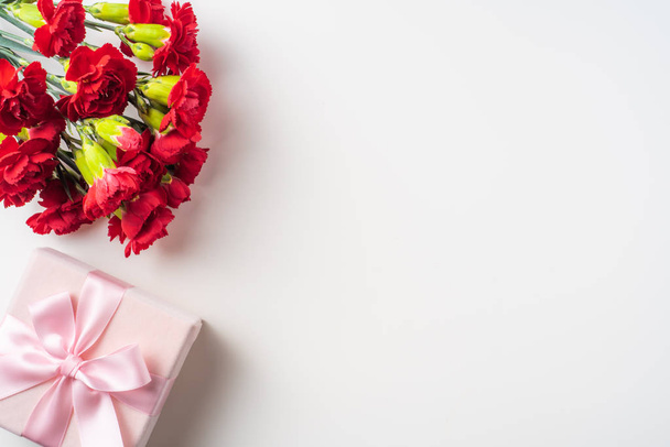 Bouquet of red carnations and gift box isolated on white background - Φωτογραφία, εικόνα