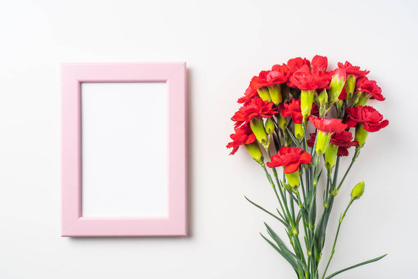 Top view of bunch of red carnations and photo frame isolated on white background - Photo, image