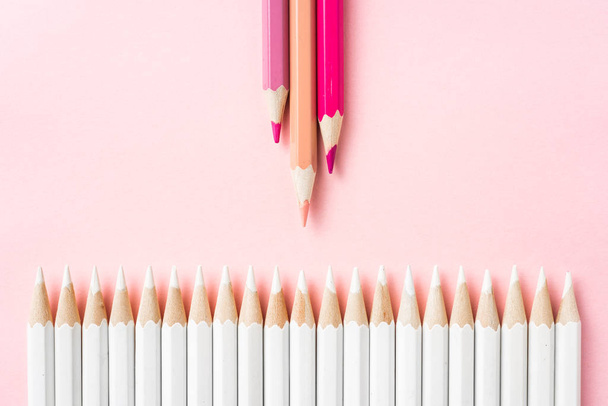 Business and design concept - lot of white pencils and colored pencils on pink paper background. Symbol of leadership, teamwork, success and unique. - Photo, Image