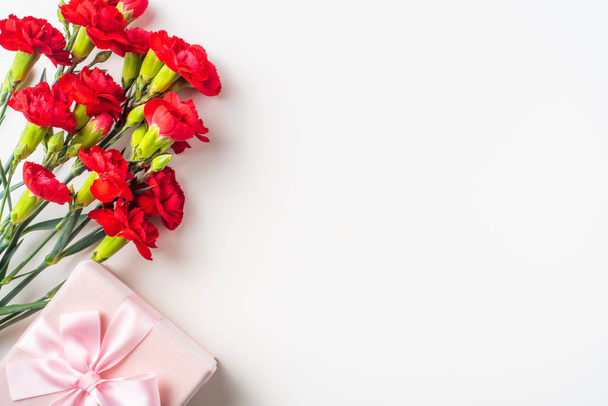 Bouquet of red carnations and gift box on background with copy space - Foto, immagini