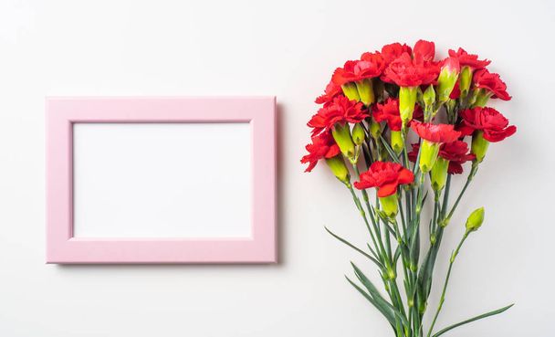 Top view of bunch of red carnations and photo frame isolated on white background - Photo, image