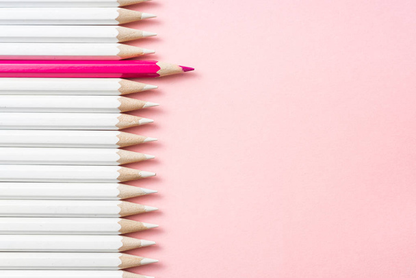 Business and design concept - lot of white pencils and one color pencil on pink paper background. Symbol of leadership, teamwork, success and unique. - 写真・画像