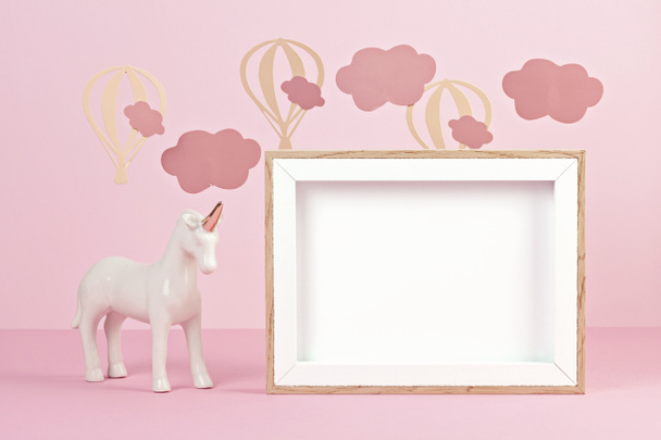 Cute white unicorn over the pink pastel background with clouds and baloons. Baby shower, girl birthday concept - Fotó, kép