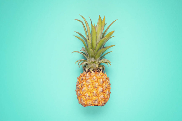 Tropical pineapple fruit top view over blue background. Summer vacation, travel, tourism concept flat lay.  - Fotó, kép