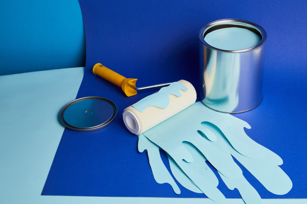 silver can and roller with dripping paper cut paint on bright blue background - Foto, Bild