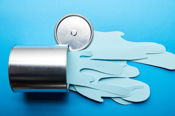 top view of spilled paper cut blue paint near silver shiny can and cap - Fotoğraf, Görsel
