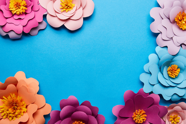 top view of multicolored paper cut flowers on blue background with copy space - Foto, immagini