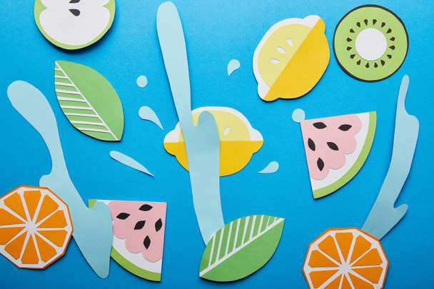 top view of paper cut water splashes with fruits on blue background - Photo, Image