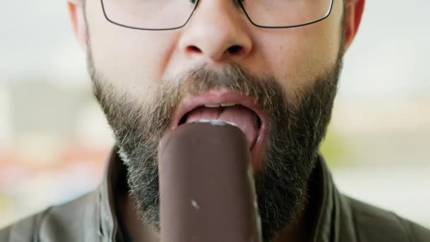 Lähikuva muotokuva nälkäinen parrakas mies syö jäätelöä - Materiaali, video
