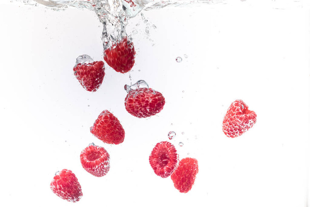 Raspberries splashing into crystal clear water with air bubbles - Фото, зображення