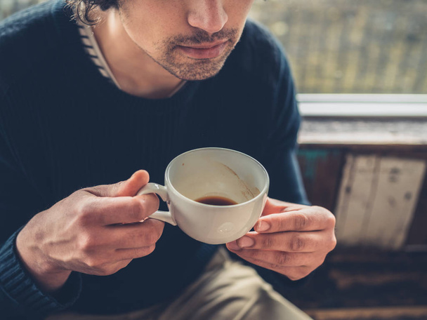 A young man is drinking coffee in a cafe - Φωτογραφία, εικόνα