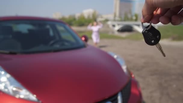 The girl snatches the keys from the mans hands and runs happily hugging a new car. 4K Slow Mo - Filmmaterial, Video