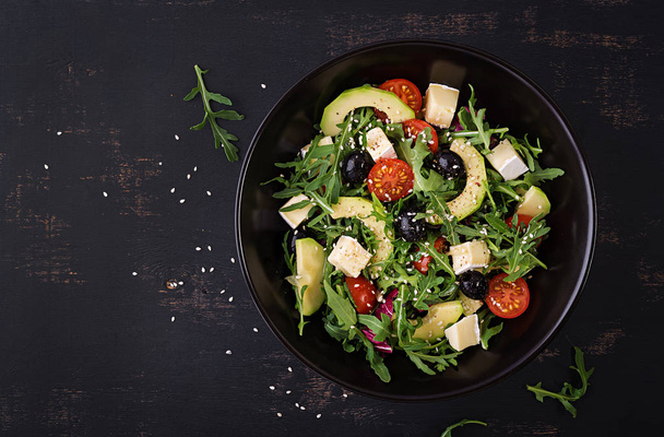 Groene salade met gesneden avocado, cherry tomaten, zwarte olijven en kaas. Gezonde voeding Vegetarische zomer groente salade. Tabel instelling. Food concept. Top View. - Foto, afbeelding