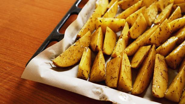 Sliced raw potatoes on a baking sheet with spices and rosemary, top view - Фото, изображение