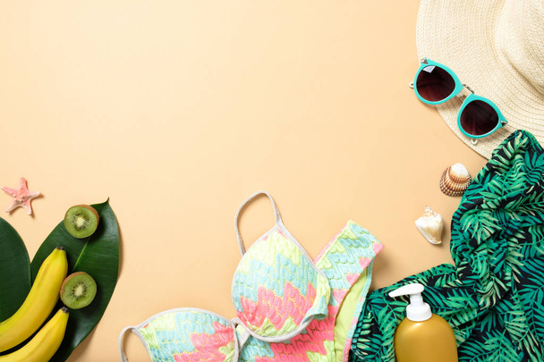 Women's beach accessories: straw hat, sunglasses, swimwear, green scarf, suntan lotion, banana on yellow background. Travel concept, summer background. Flat lay composition, top view, overhead. - Foto, Bild