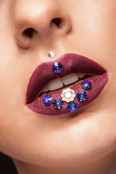 Close-up van mooie womna met mate creatieve lippenstift en diamanten bloemen - Foto, afbeelding