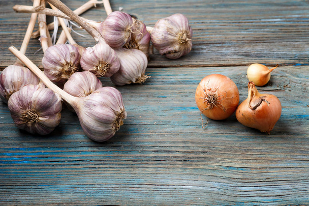 violet garlic and orange onion on a wooden background - Fotó, kép